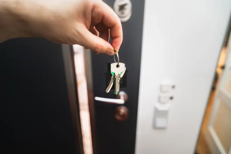 Clés d'une maison tenues devant la porte d'entrée