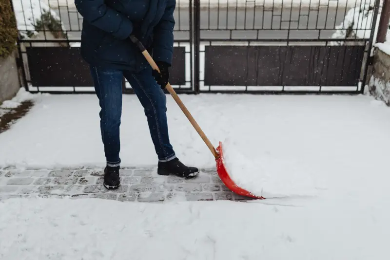 Déneigement à la pelle d'une allée devant une maison
