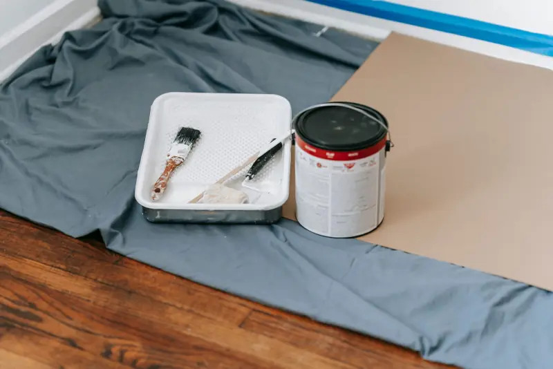 Rouleau, pinceaux et bac à peinture sur une bâche de protection
